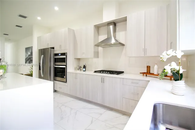 a kitchen with stainless steel appliances kitchen island granite countertop a refrigerator a stove and a sink