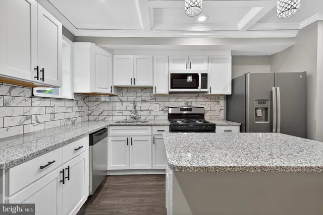a kitchen with stainless steel appliances granite countertop a sink a stove top oven a refrigerator and dishwasher