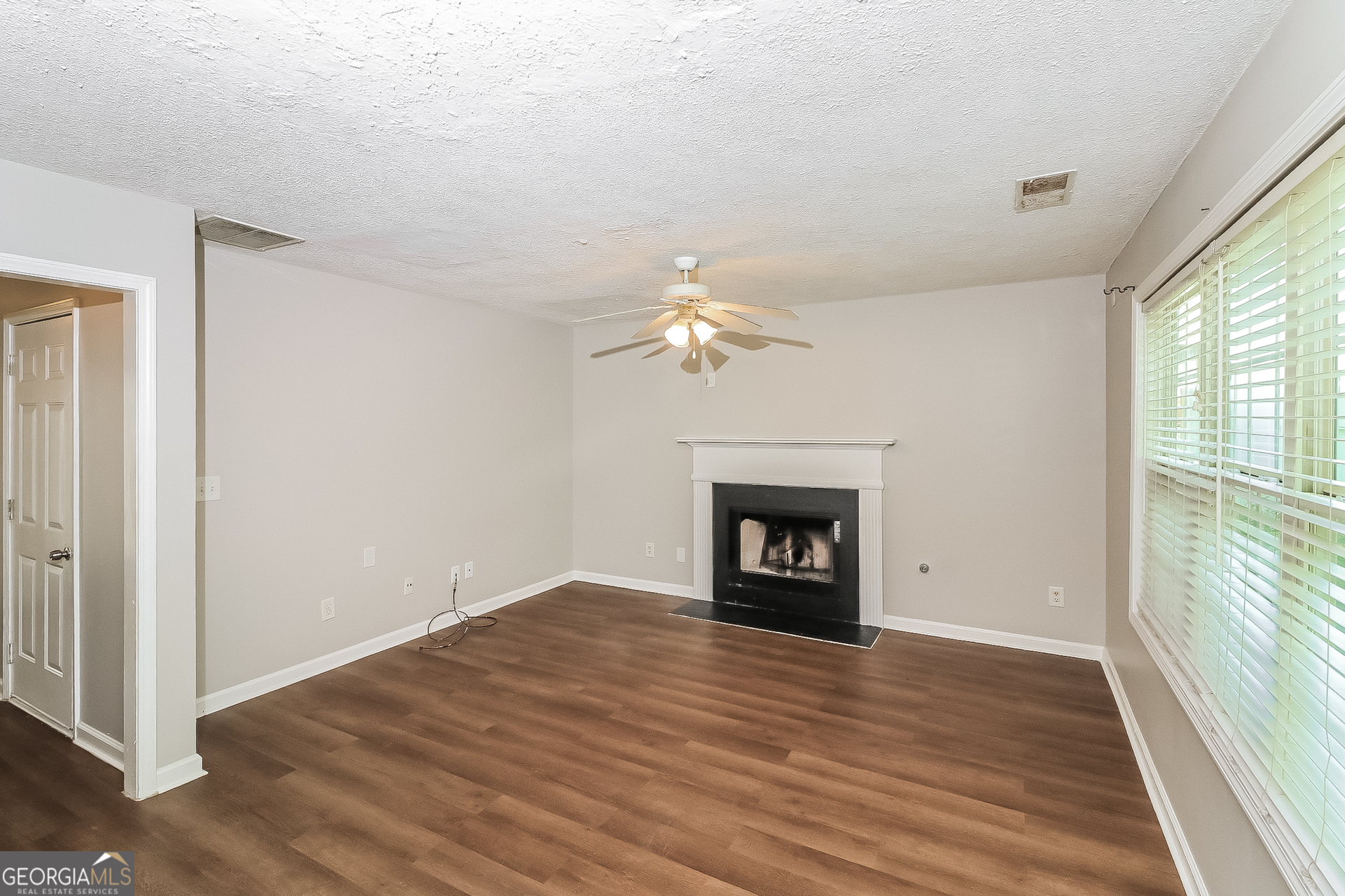 59 Greystone Ridge Hiram, GA 30141 - Photo 6 of 15 an empty room with wooden floor a fireplace and windows