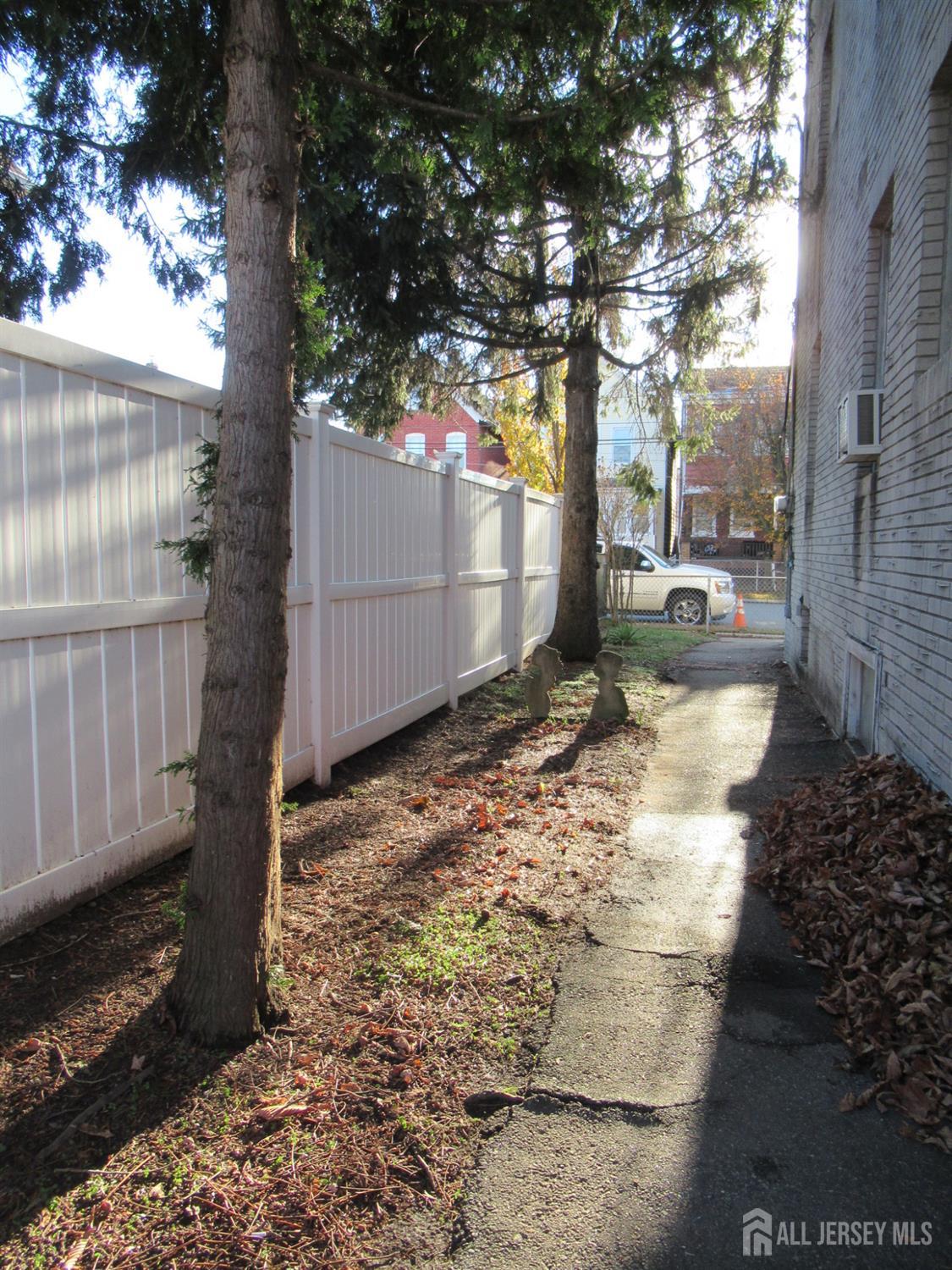 82 Pulaski Avenue Carteret, NJ 07008 - Photo 8 of 47 a view of a backyard with large trees and wooden fence