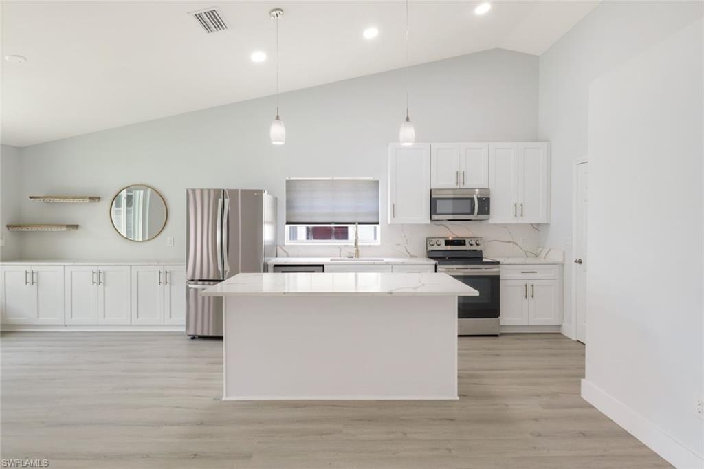 12800 Eagle Pointe Circle Fort Myers, FL 33913 - Photo 11 of 28 a kitchen with stainless steel appliances granite countertop a stove top oven a sink a refrigerator white cabinets and wooden floor