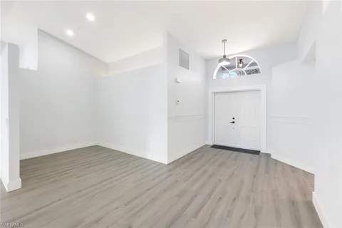 an empty room with wooden floor and ceiling fan