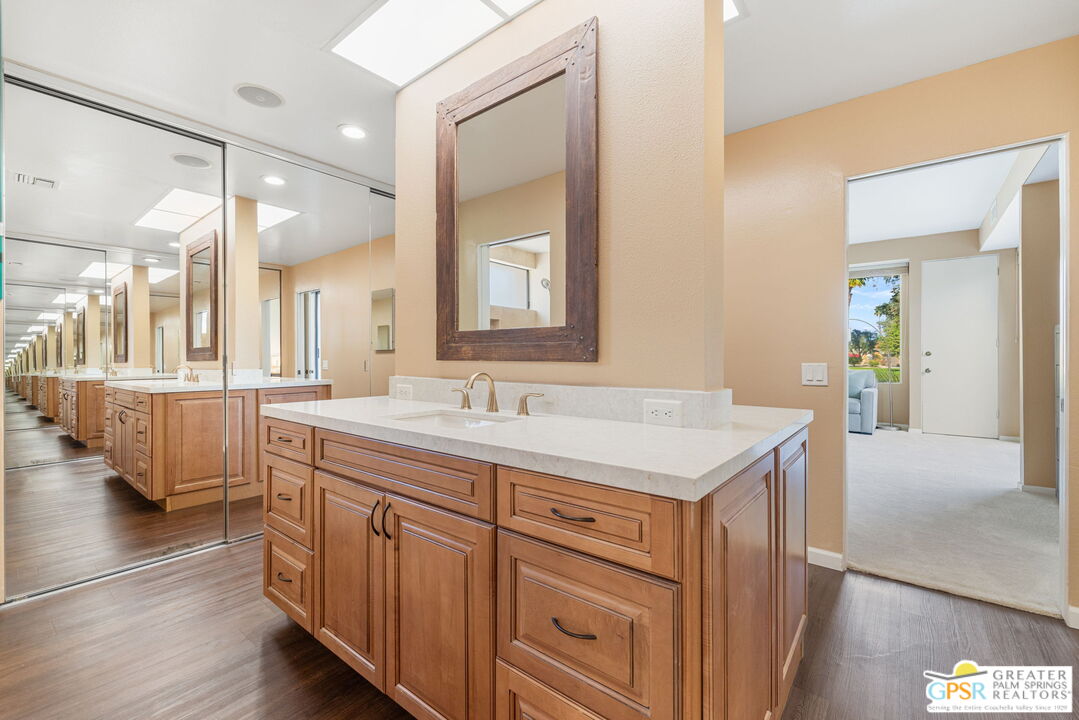 651 Hospitality Drive Rancho Mirage, CA 92270 - Photo 36 of 44 a bathroom with a granite countertop sink a large mirror and a bathtub