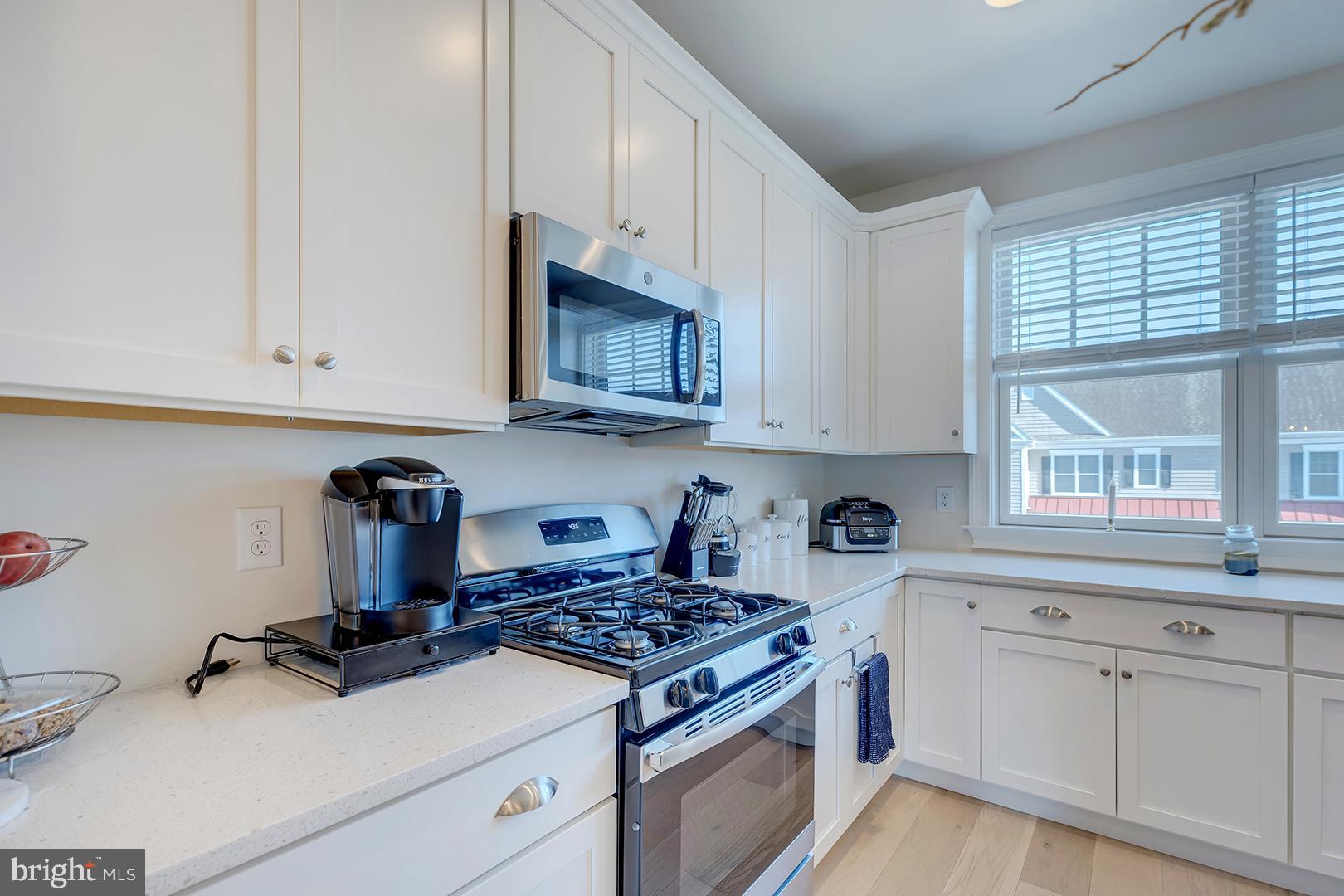 18799 Bethpage Drive, Unit 16E Lewes, DE 19958 - Photo 14 of 68 a kitchen with granite countertop a stove a sink dishwasher and white cabinets with wooden floor