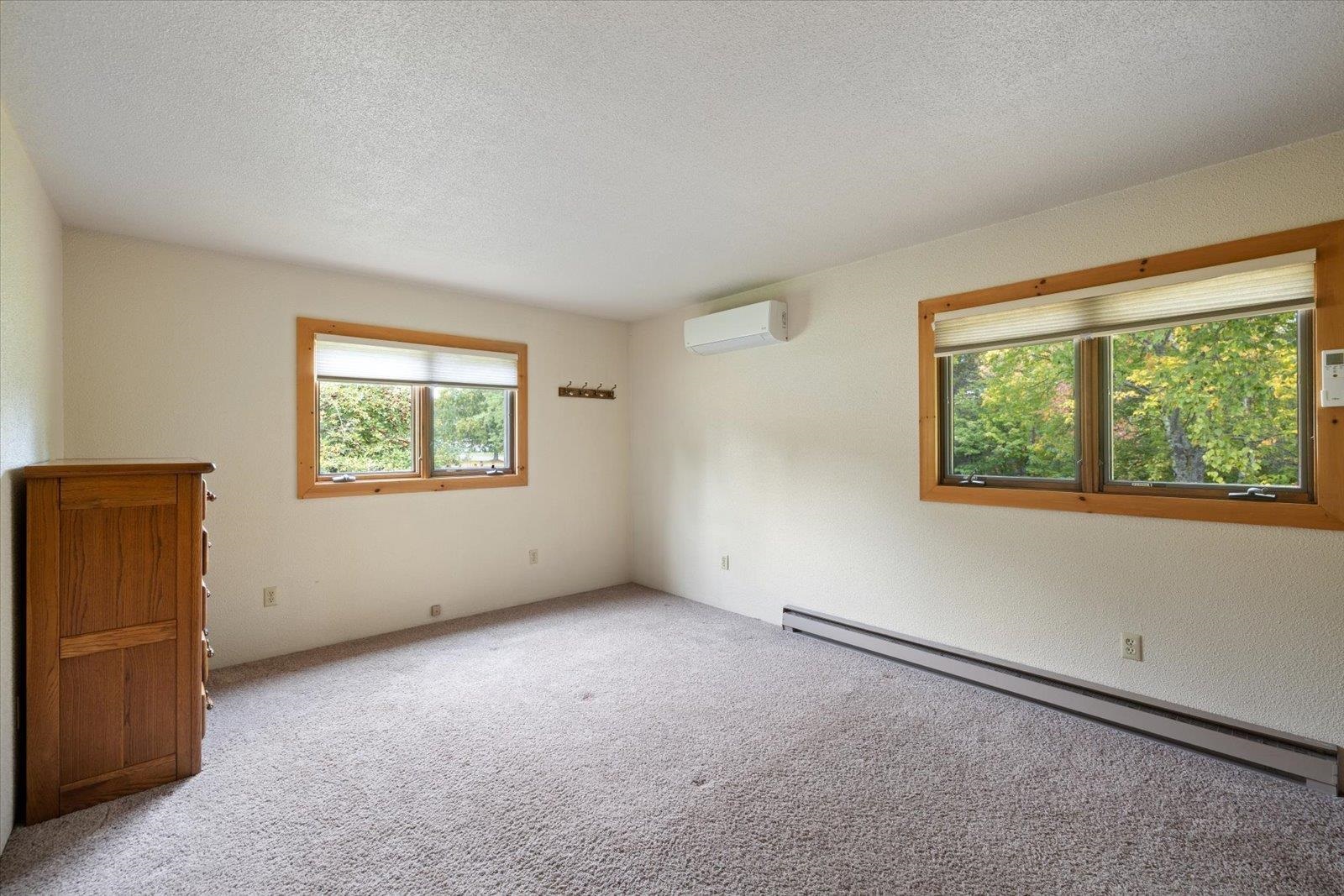 236 East Ahola Road Ely, MN 55731 - Photo 18 of 27 Empty room featuring a baseboard radiator, carpet floors, a textured ceiling, and a wall unit AC