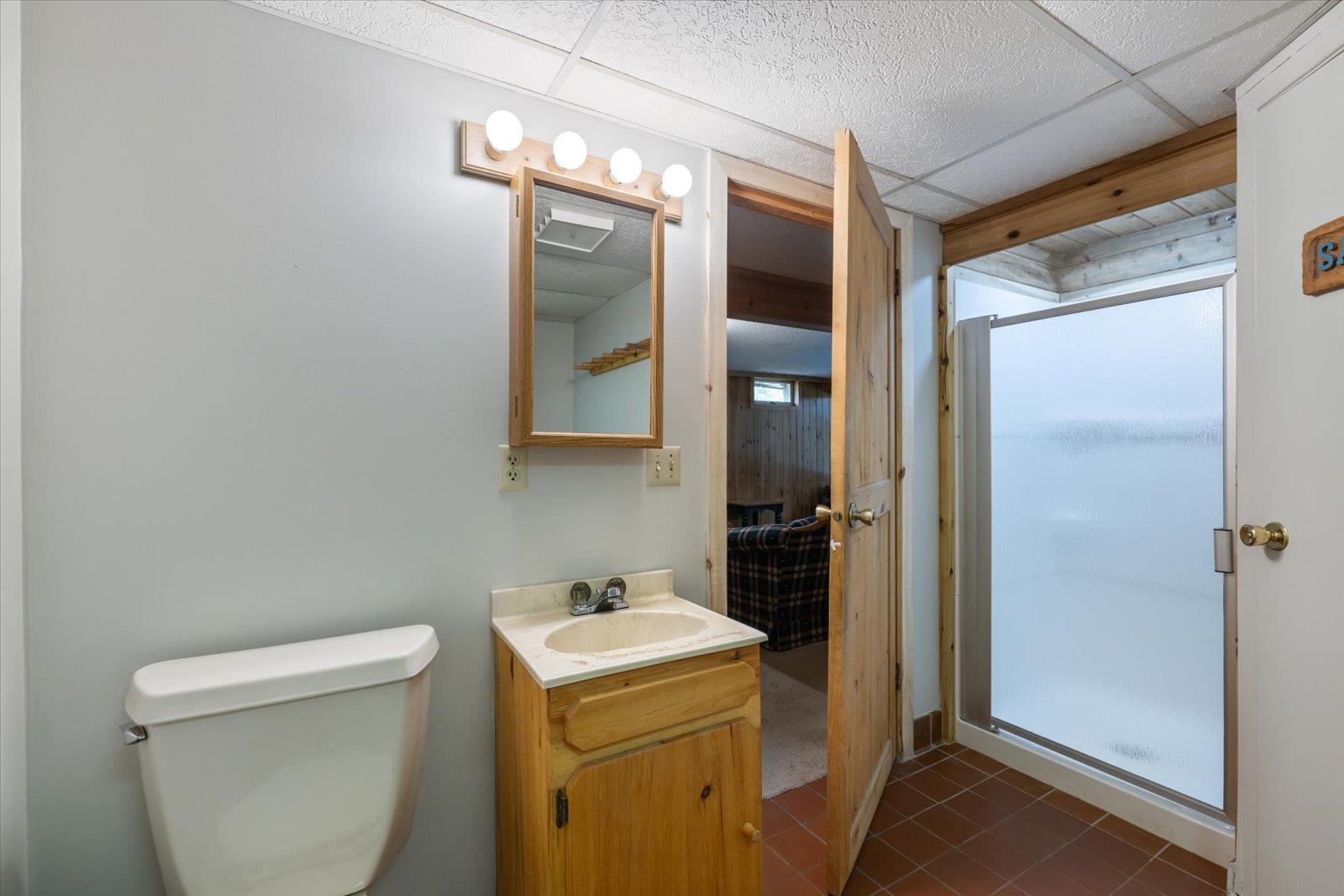 236 East Ahola Road Ely, MN 55731 - Photo 19 of 27 Bathroom with a shower stall, vanity, dark tile patterned floors, and a drop ceiling