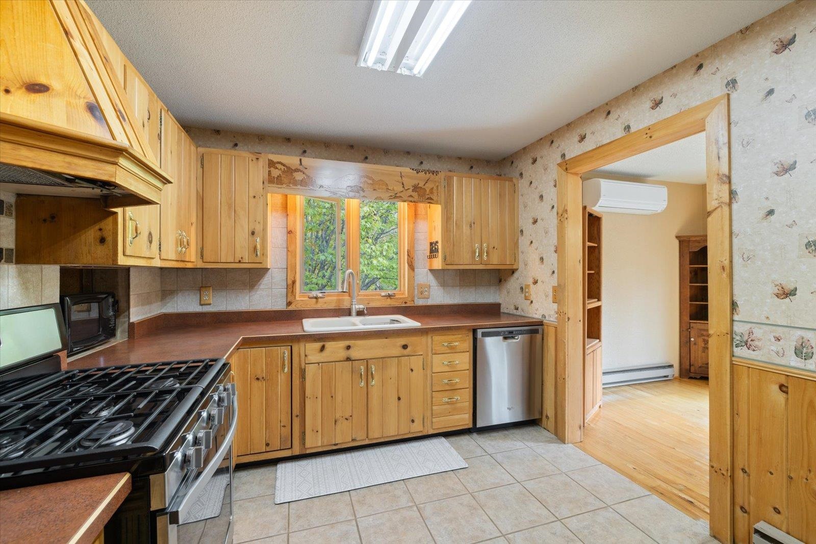 236 East Ahola Road Ely, MN 55731 - Photo 3 of 27 Kitchen with appliances with stainless steel finishes, custom exhaust hood, light tile patterned floors, wallpapered walls, and dark countertops
