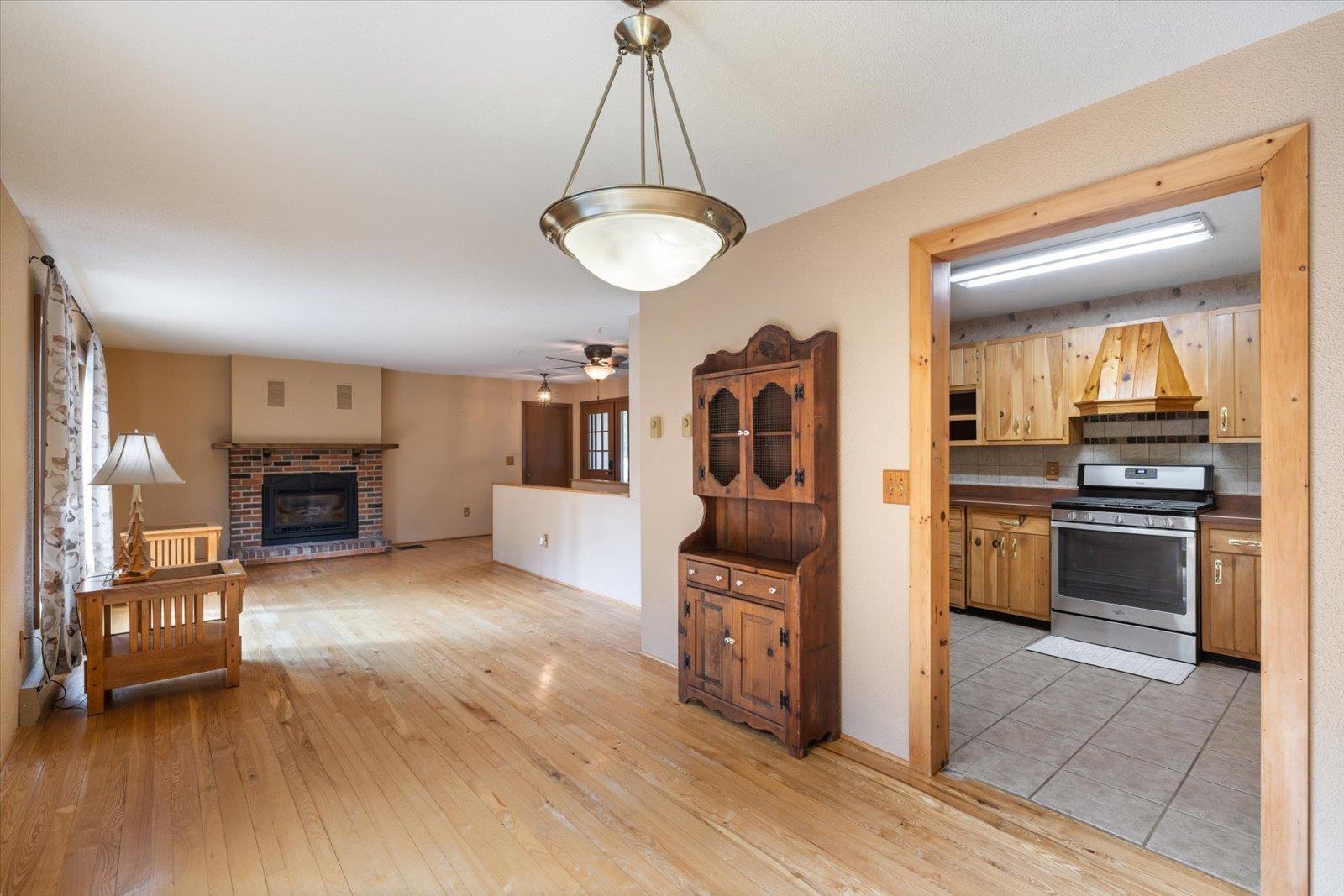 236 East Ahola Road Ely, MN 55731 - Photo 7 of 27 Kitchen featuring gas range, light wood-type flooring, a ceiling fan, and a brick fireplace