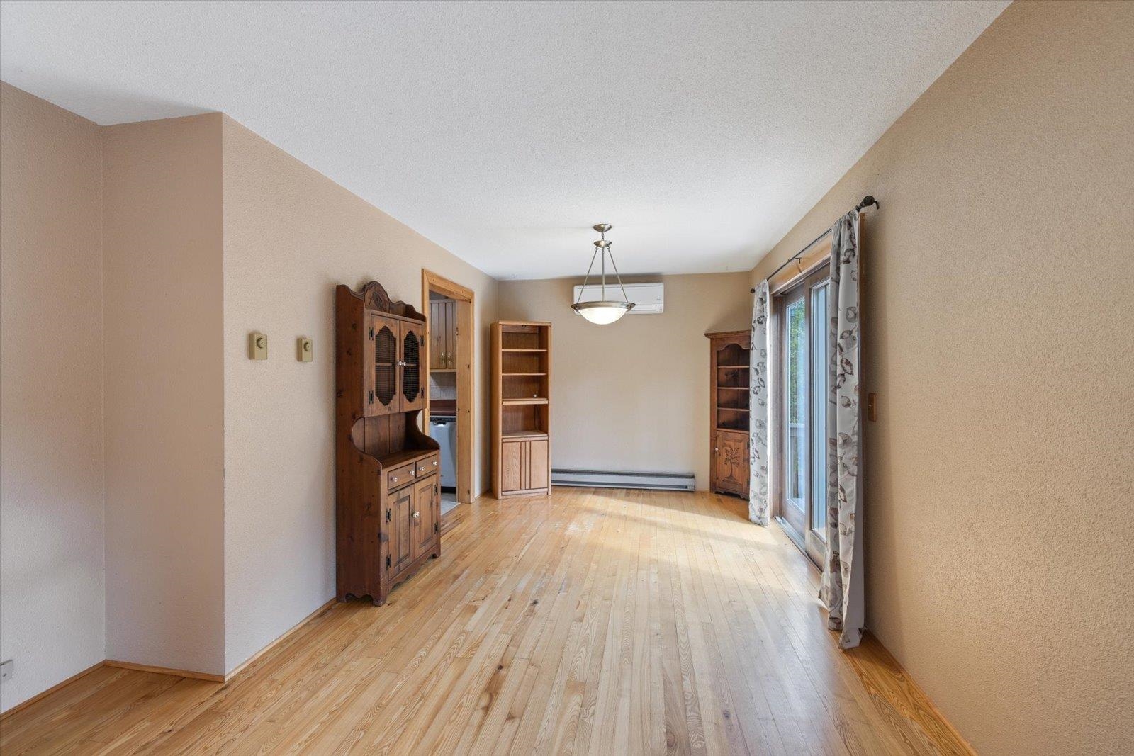 236 East Ahola Road Ely, MN 55731 - Photo 8 of 27 Unfurnished dining area with light wood finished floors, baseboard heating, a textured wall, and a wall unit AC