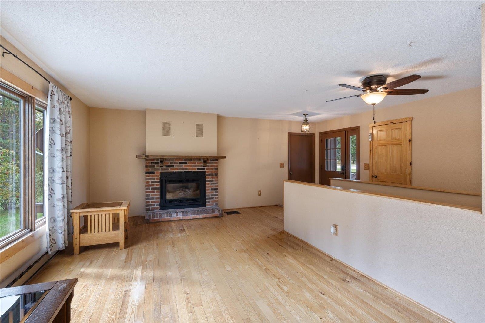 236 East Ahola Road Ely, MN 55731 - Photo 9 of 27 Unfurnished living room featuring a fireplace, light wood-type flooring, and a ceiling fan