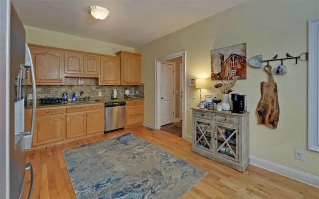 a kitchen with stainless steel appliances granite countertop a refrigerator a stove a sink a dining table and chairs with wooden floor