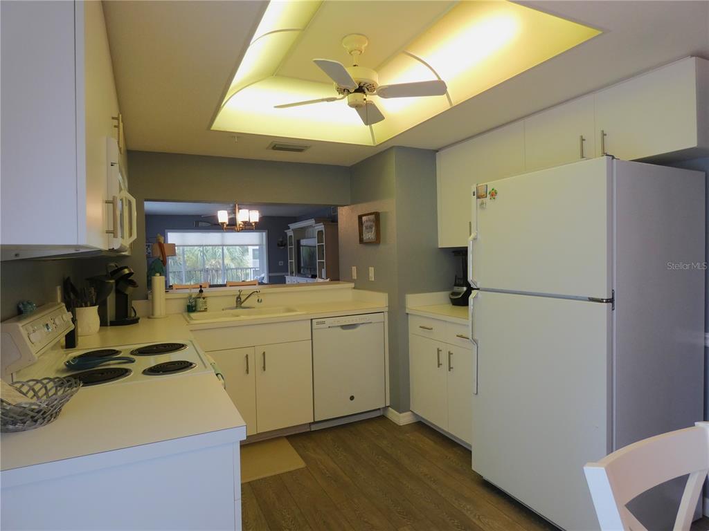 9320 Clubside Circle, Unit 2208 Sarasota, FL 34238 - Photo 6 of 41 a kitchen with a refrigerator a stove a sink a chimney and wooden floor