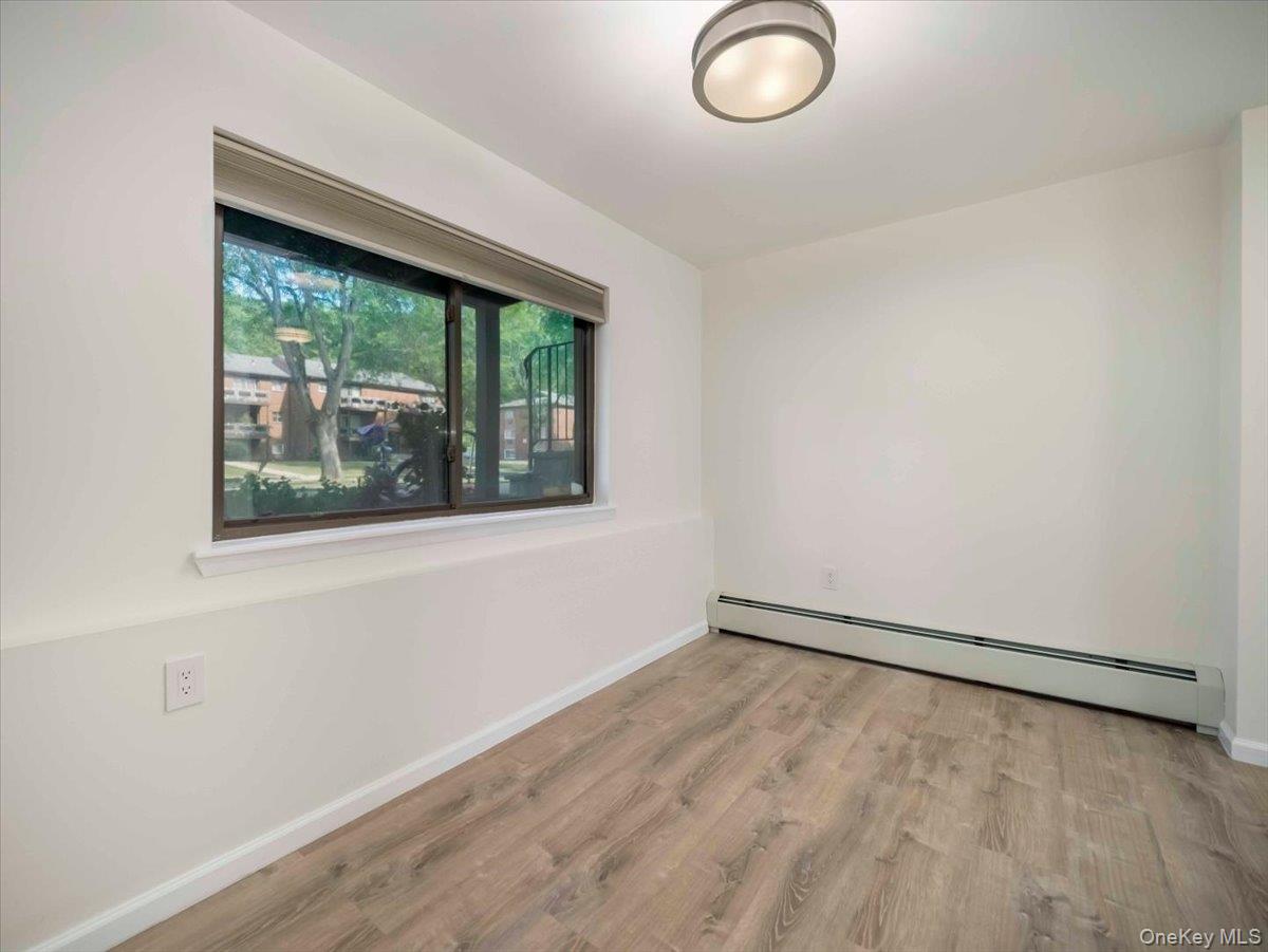 27 Tanager Road, Unit 2702 Monroe, NY 10950 - Photo 14 of 35 Room featuring wood-finish flooring, white painted walls, and a window with a roller shade