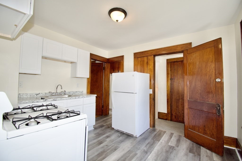 19 Ambrose Street Springfield, MA 01109 - Photo 17 of 32 a kitchen with a refrigerator a stove top oven cabinets and a wooden floor