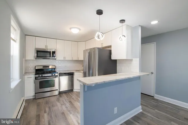 a kitchen with stainless steel appliances granite countertop a refrigerator a stove and a sink with wooden floor