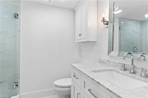 a bathroom with a granite countertop sink a toilet and a mirror