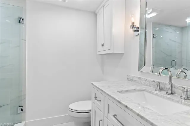 a bathroom with a granite countertop sink a toilet and a mirror