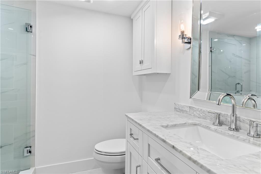 900 8th Avenue South, Unit 105 Naples, FL 34102 - Photo 12 of 20 a bathroom with a granite countertop sink a toilet and a mirror