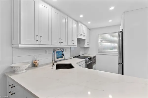 a kitchen with stainless steel appliances granite countertop a sink a stove and a refrigerator with wooden cabinets