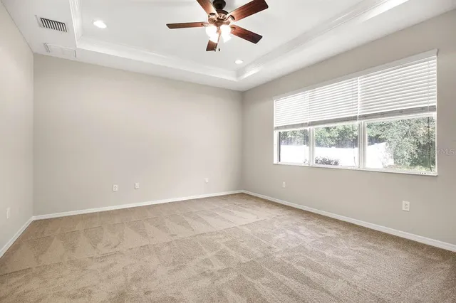 an empty room with a chandelier fan and windows
