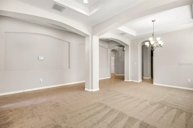a view of an empty room with a chandelier fan