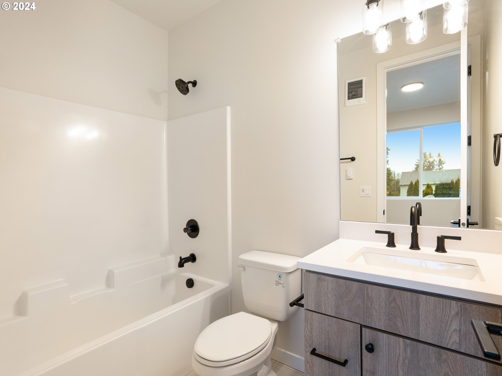 8524 North Endicott Avenue, Unit 2 Portland, OR 97217 - Photo 11 of 12 a bathroom with a sink a toilet a mirror a bathtub and shower