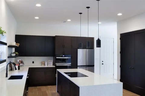 a kitchen with stainless steel appliances kitchen island granite countertop a refrigerator a oven a sink and a stove with wooden floor