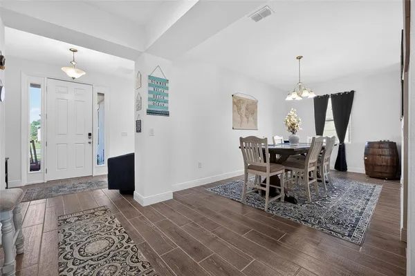 a kitchen with stainless steel appliances a stove top oven a sink dishwasher a refrigerator and a dining table with wooden floor