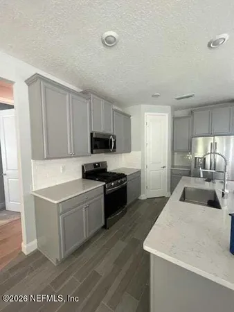 a kitchen with a sink a stove top oven and white kitchen