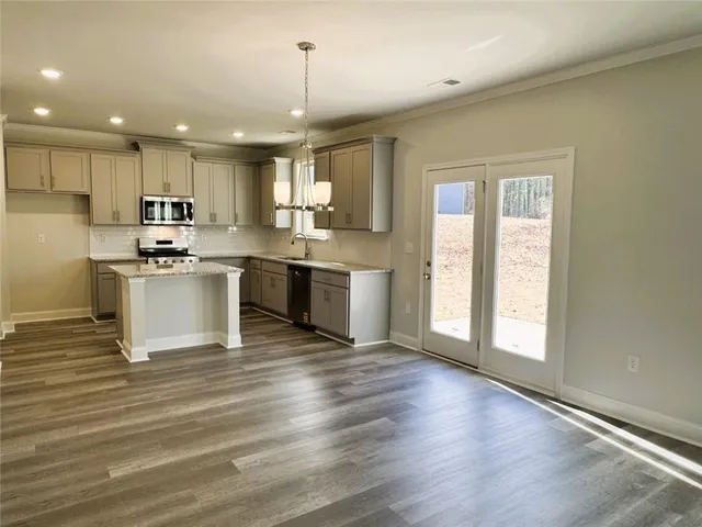 a kitchen with stainless steel appliances granite countertop a sink a stove and a wooden floors