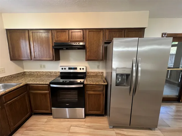 a kitchen with stainless steel appliances granite countertop a refrigerator and a sink