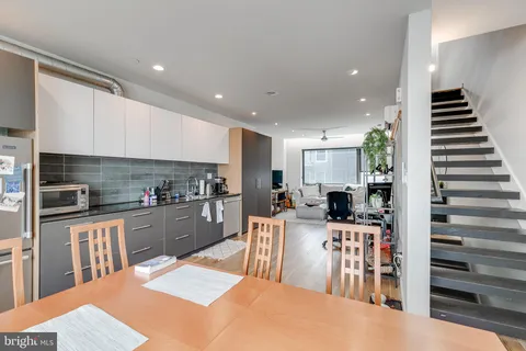 a kitchen with stainless steel appliances kitchen island granite countertop a refrigerator oven a sink dishwasher and white cabinets with wooden floor