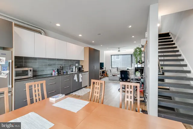 a kitchen with stainless steel appliances kitchen island granite countertop a refrigerator oven a sink dishwasher and white cabinets with wooden floor