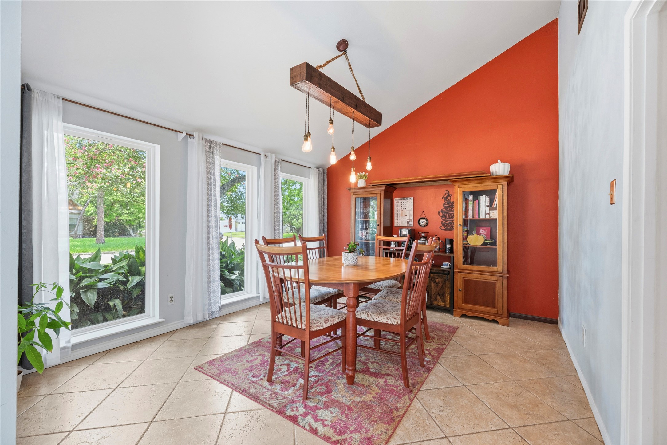 14203 Wickersham Lane Houston, TX 77077 - Photo 7 of 25 Elegant formal dining space highlighting a dramatic vaulted ceiling, low-maintenance tiled flooring, an accent wall, and three large vertical floor-to-ceiling windows looking out to the front greenery. Updated windows allow clear views of the lush landscaping.
