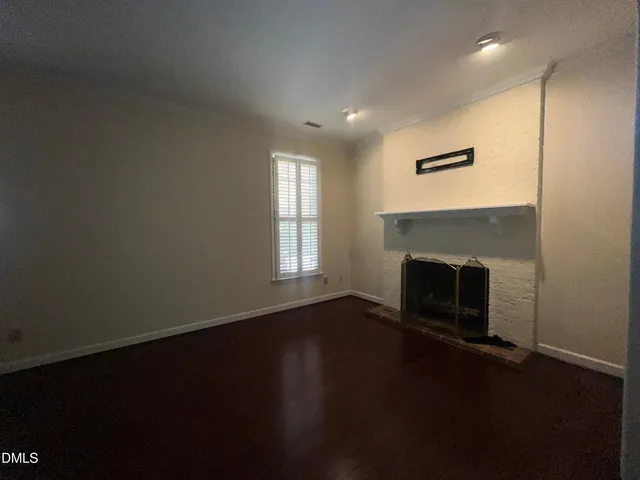 an empty room with wooden floor a fireplace and windows