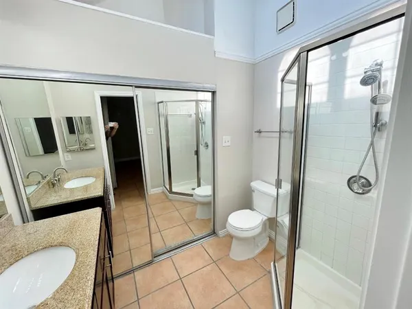 a bathroom with a granite countertop sink a toilet a mirror and shower