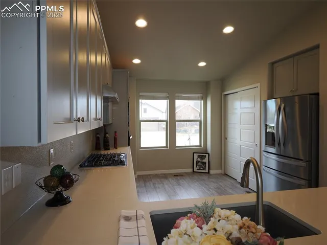 a kitchen with refrigerator and wooden floor