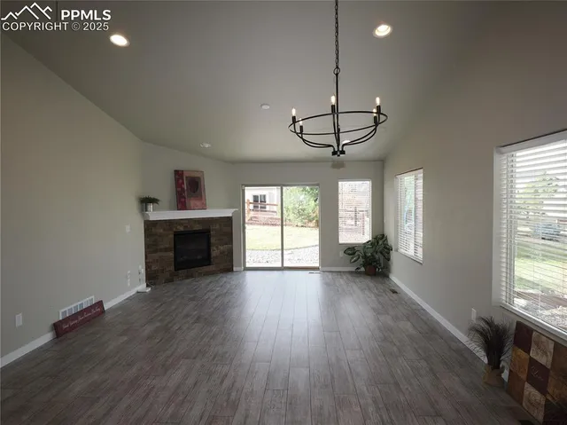 a view of an empty room with wooden floor fireplace and a window
