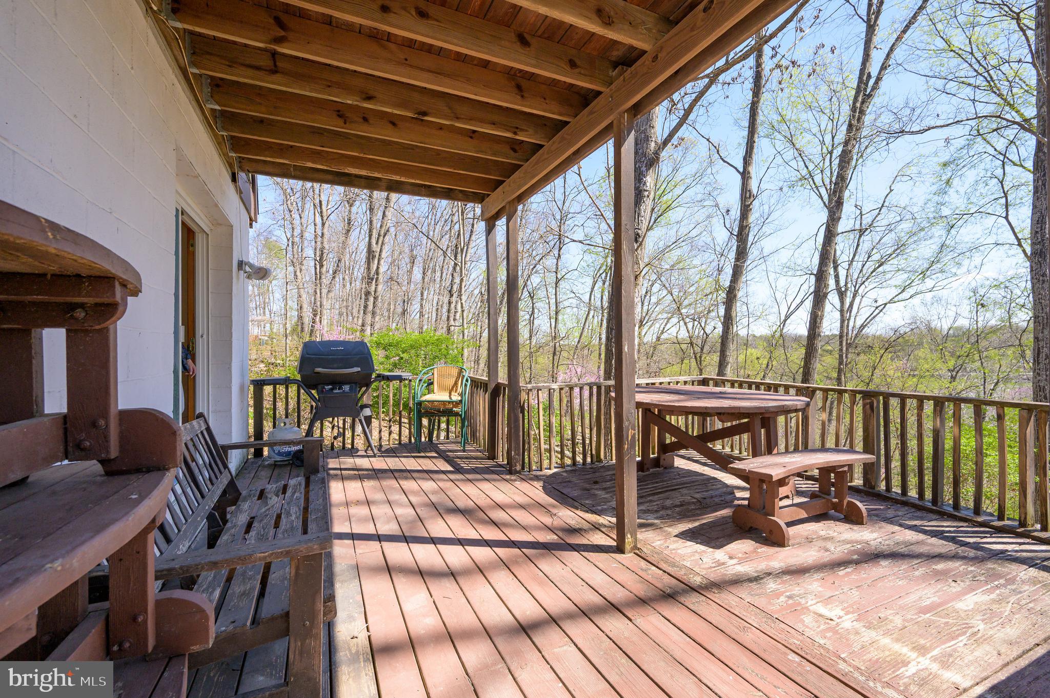1524 Lamplight Road Bunker Hill, WV 25413 - Photo 24 of 44 a view of a patio with table and chairs couches with wooden floor and fence