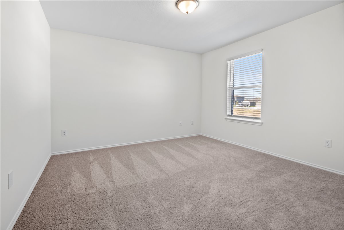 18501 Spotted Eagle Lane Elgin, TX 78621 - Photo 20 of 40 A well-lit bedroom features plush carpeting and ample natural illumination from a wide window.