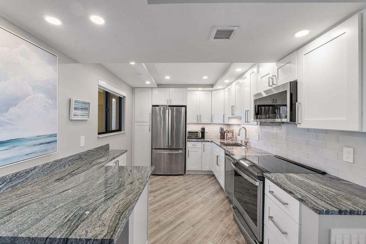 200 Ocean Trail Way, Unit 602 Jupiter, FL 33477 - Photo 12 of 50 a kitchen with stainless steel appliances granite countertop a refrigerator stove microwave and sink