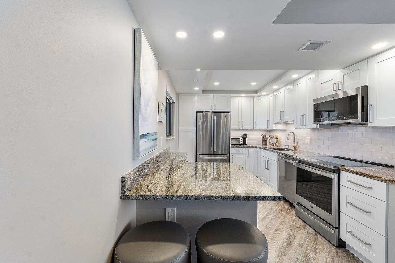 200 Ocean Trail Way, Unit 602 Jupiter, FL 33477 - Photo 10 of 50 a kitchen with a table chairs microwave and refrigerator