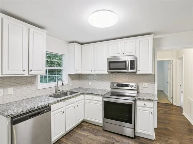 a kitchen with granite countertop white cabinets and stainless steel appliances