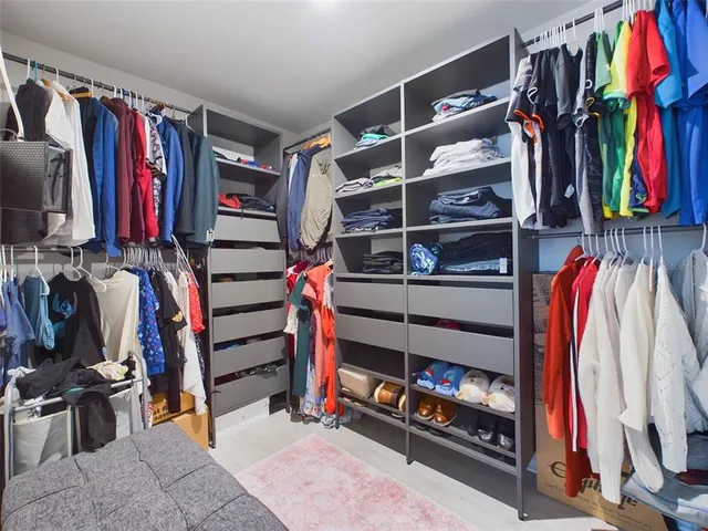 a view of walk in closet with clothes and shoes