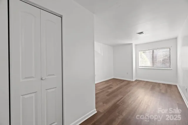 an empty room with wooden floor closet and windows