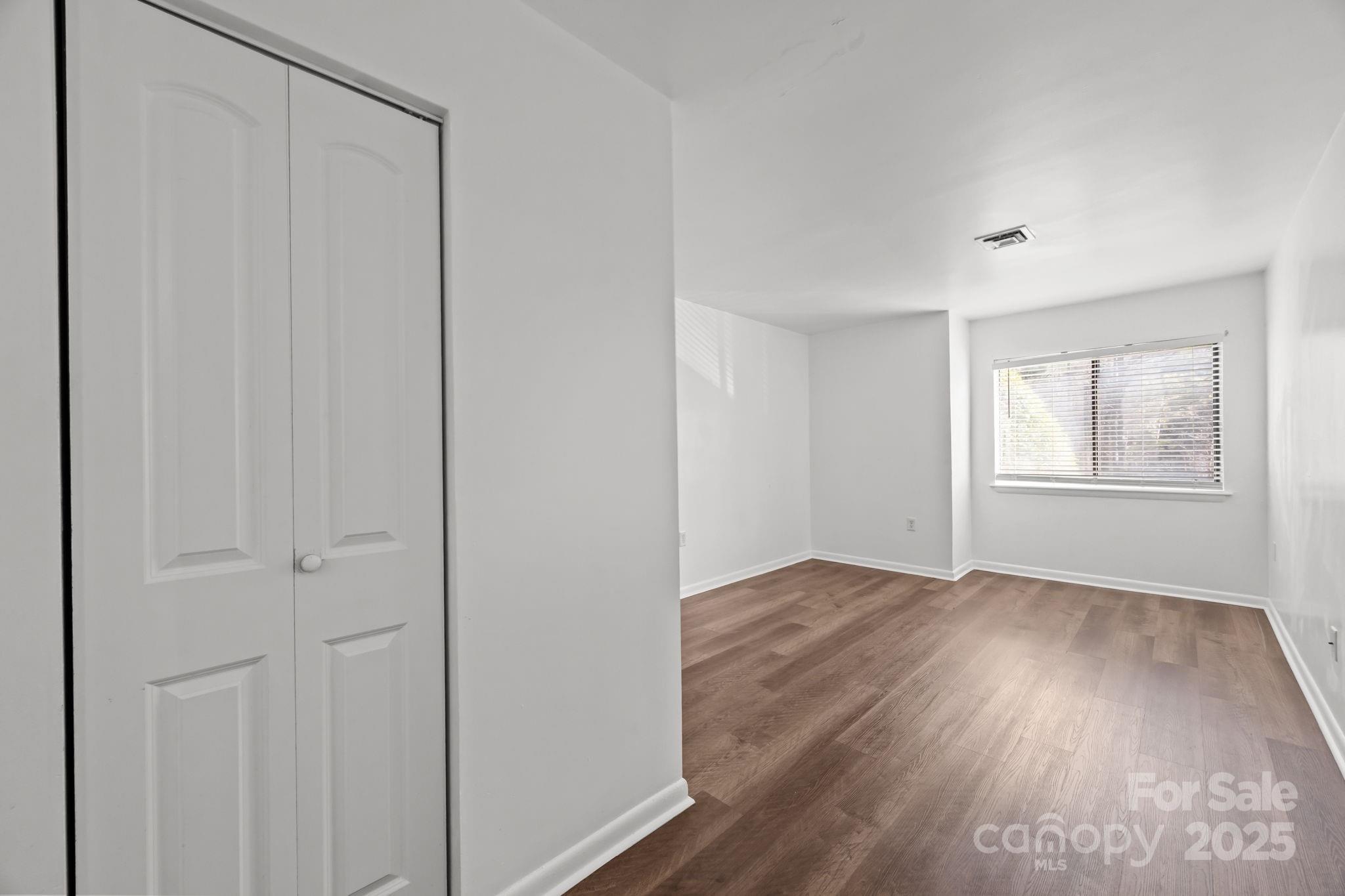 4902 Spring Lake Drive, Unit D Charlotte, NC 28212 - Photo 14 of 30 an empty room with wooden floor closet and windows