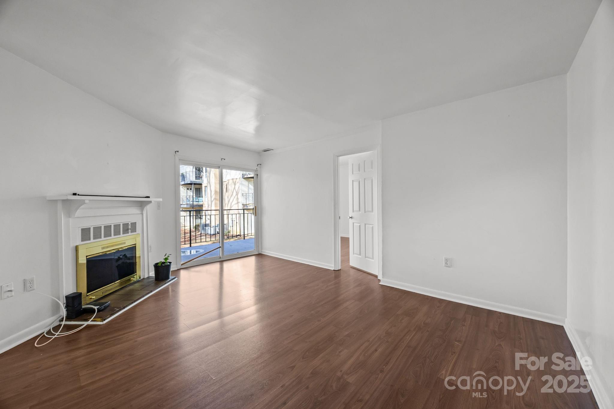4902 Spring Lake Drive, Unit D Charlotte, NC 28212 - Photo 7 of 30 an empty room with floor to ceiling window and fireplace