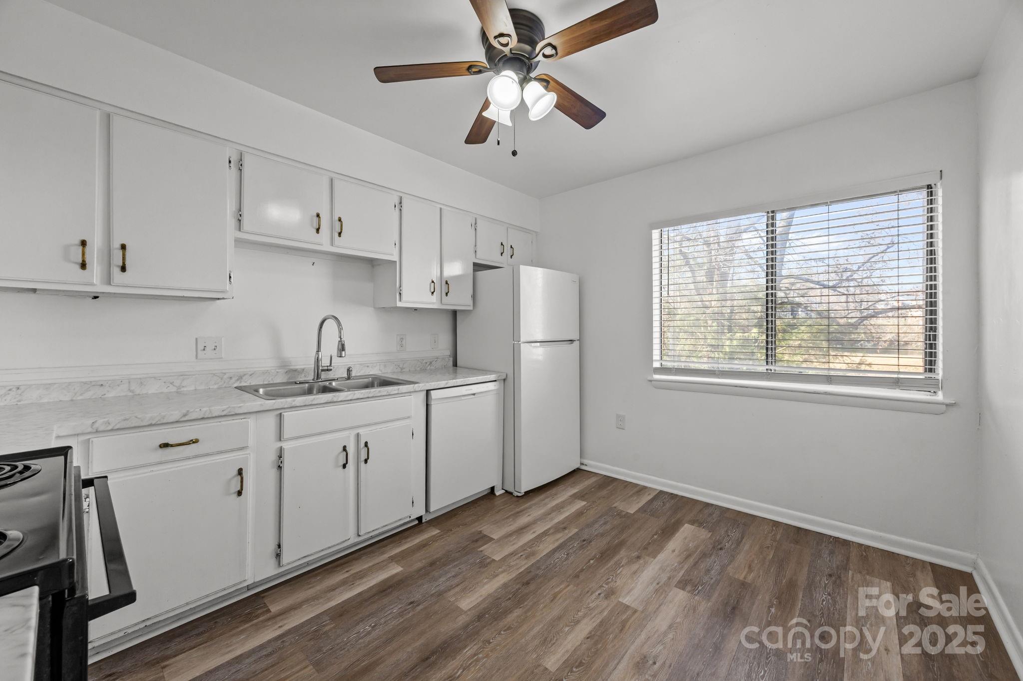 4902 Spring Lake Drive, Unit D Charlotte, NC 28212 - Photo 10 of 30 a kitchen with granite countertop white cabinets white appliances a sink and a window