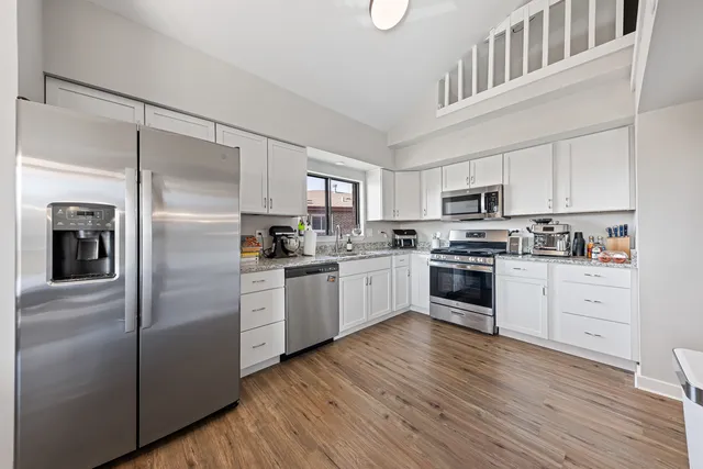 a kitchen with white cabinets stainless steel appliances and a refrigerator
