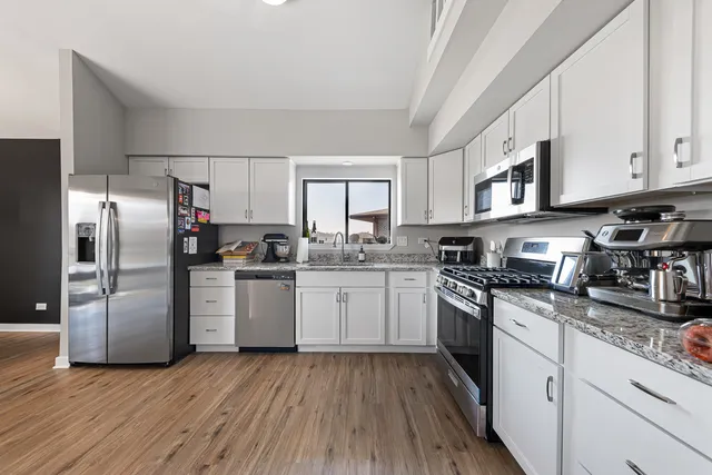 a kitchen with granite countertop a refrigerator stove top oven and sink